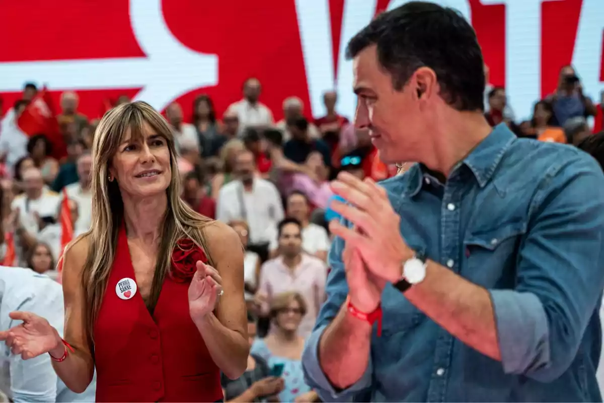 Personas aplaudiendo en un evento con fondo rojo y multitud de gente. Personas aplaudiendo en un evento con fondo rojo y multitud de gente.