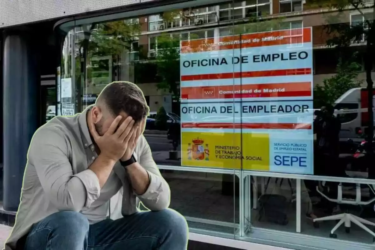 Un hombre con las manos en la cara sentado frente a una oficina de empleo en Madrid.