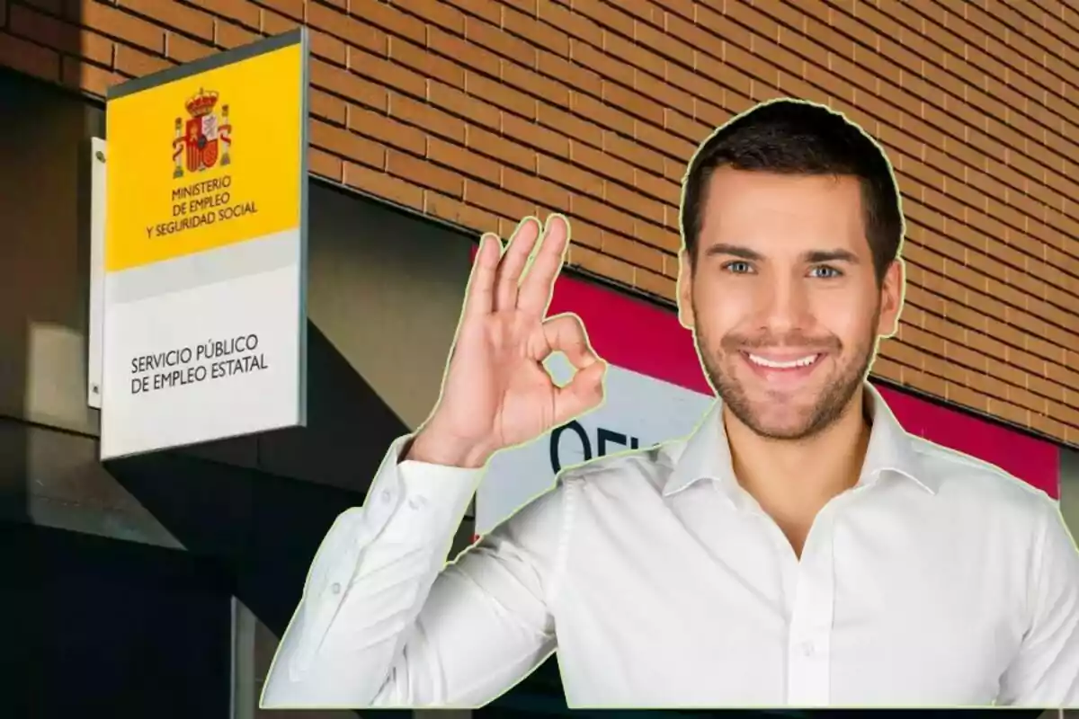 Un hombre sonriente hace un gesto de "OK" con la mano frente a un edificio del Ministerio de Empleo y Seguridad Social de España.