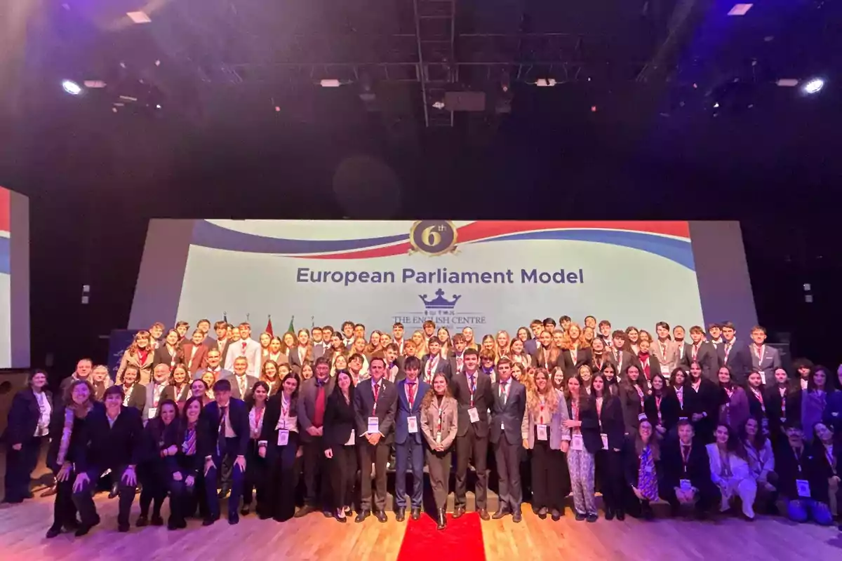 Un grupo grande de personas posando en un escenario frente a una pantalla que dice "European Parliament Model".