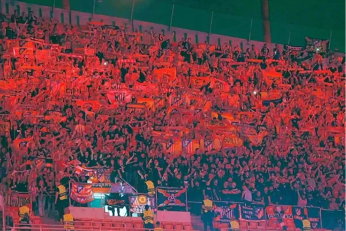 Una multitud de aficionados en un estadio de fútbol, todos vestidos de rojo y sosteniendo bufandas y banderas, creando un ambiente vibrante y lleno de energía. Una multitud de aficionados en un estadio de fútbol, todos vestidos de rojo y sosteniendo bufandas y banderas, creando un ambiente vibrante y lleno de energía.