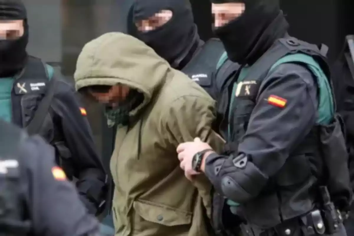 A group of Civil Guard officers arrests a hooded person.