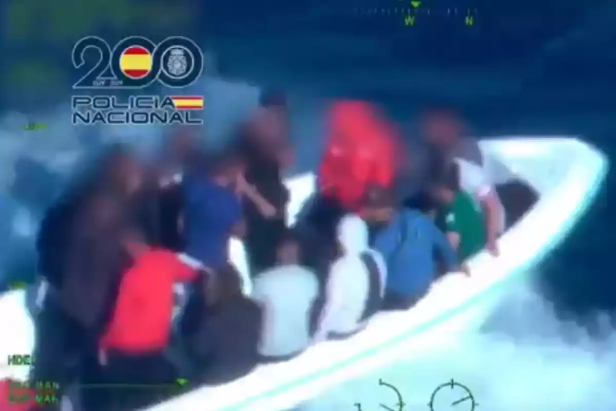 Varias personas viajan en una lancha rápida sobre el mar con el logo de la Policía Nacional de España en la esquina superior izquierda Varias personas viajan en una lancha rápida sobre el mar con el logo de la Policía Nacional de España en la esquina superior izquierda