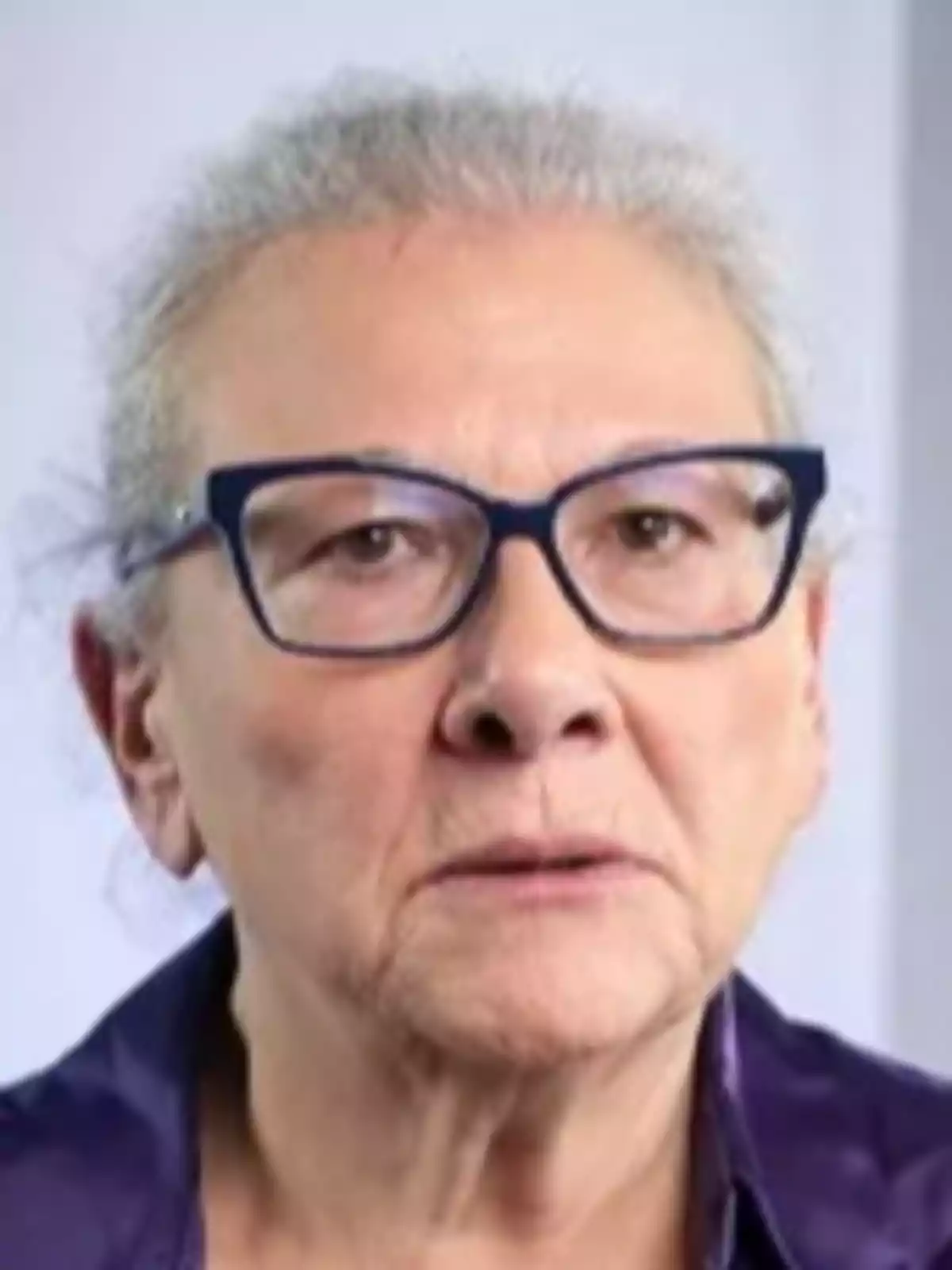 An older person with glasses and grey hair tied back, wearing a dark jersey. An older person with glasses and grey hair tied back, wearing a dark jersey.