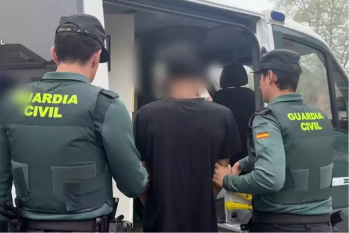 Dos agentes de la Guardia Civil escoltan a una persona hacia un vehículo oficial. Dos agentes de la Guardia Civil escoltan a una persona hacia un vehículo oficial.
