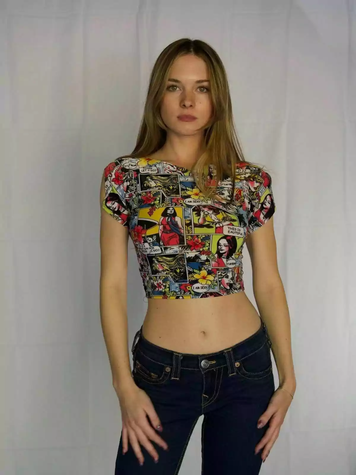 Stella del Carmen Banderas with long blonde hair wears a cropped T-shirt with a comic book design and skinny jeans, posing in front of a white background. Post on Instagram on March 1, 2021 Stella del Carmen Banderas with long blonde hair wears a cropped T-shirt with a comic book design and skinny jeans, posing in front of a white background. Post on Instagram on March 1, 2021