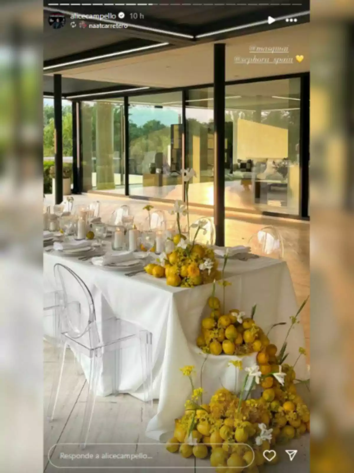 Mesa elegante decorada con limones y flores amarillas en un espacio moderno con paredes de cristal y sillas transparentes Mesa elegante decorada con limones y flores amarillas en un espacio moderno con paredes de cristal y sillas transparentes