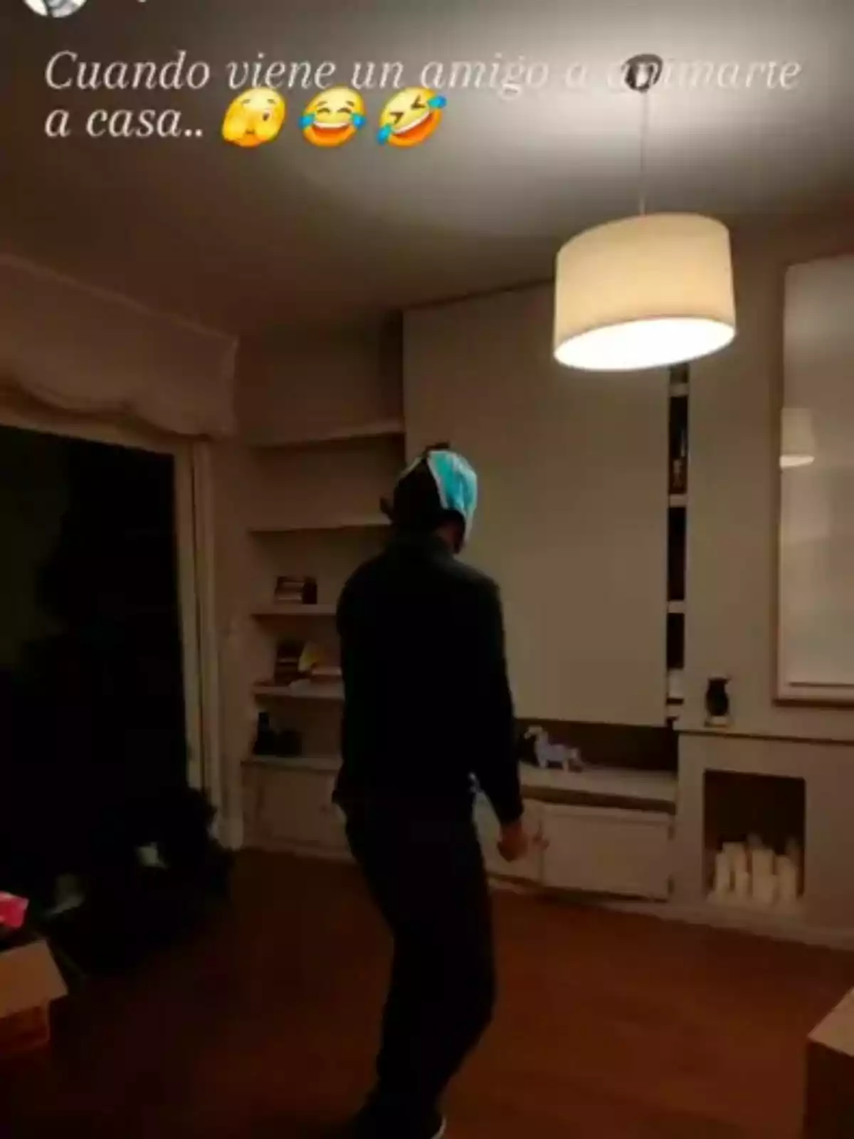 Un hombre con una bolsa en la cabeza está de pie en una sala iluminada con una lámpara colgante. Un hombre con una bolsa en la cabeza está de pie en una sala iluminada con una lámpara colgante.