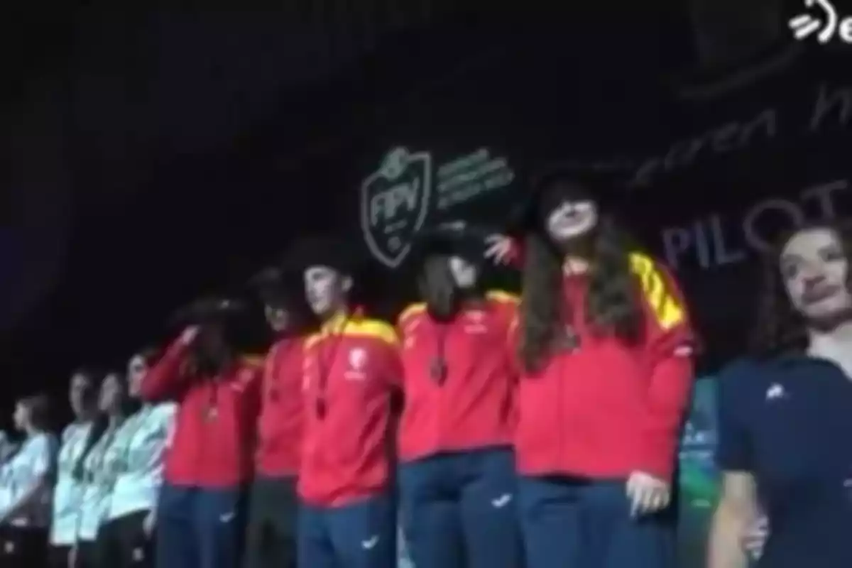 Equipo femenino con uniforme rojo y amarillo en una ceremonia de premiación deportiva