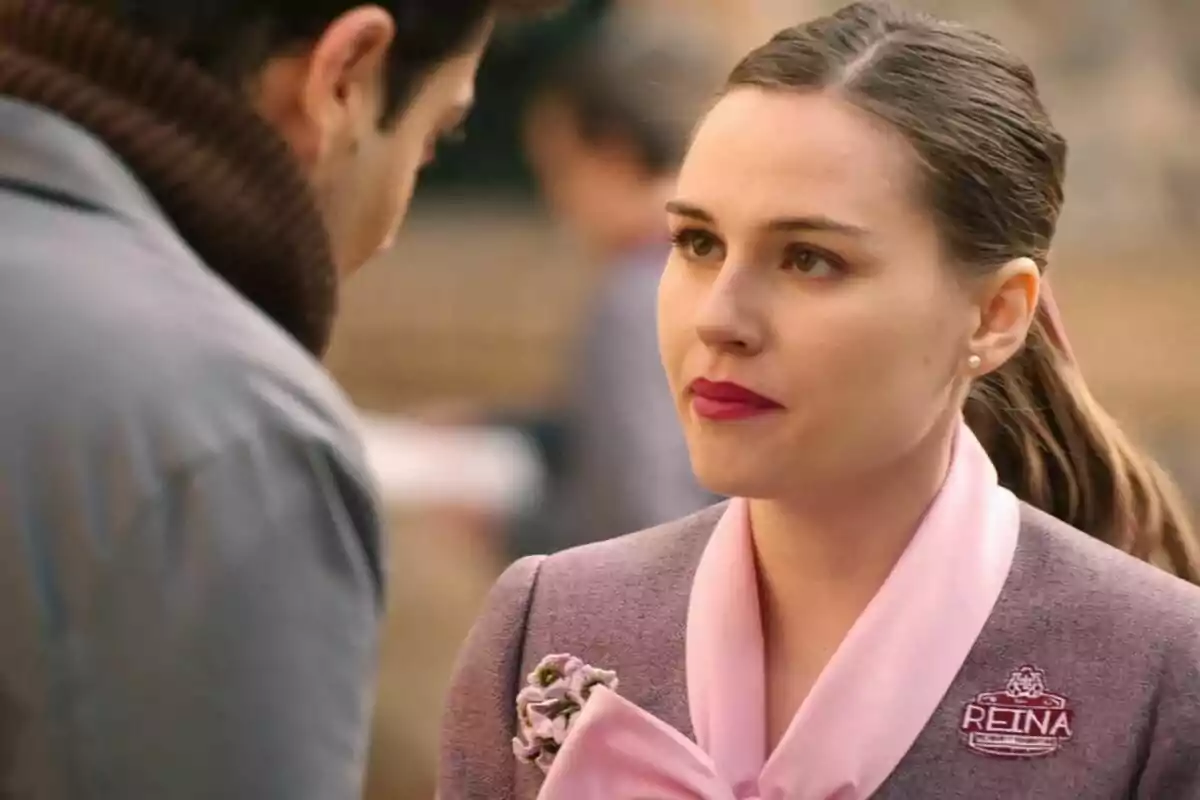 Claudia con un uniforme rosa y gris, con una insignia que dice 