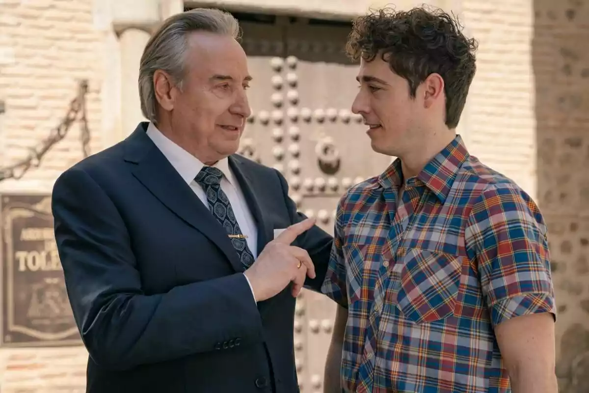 Don Pedro y Mateo conversando frente a una puerta antigua, uno de ellos lleva traje y el otro una camisa a cuadros. Captura de 'Sueños de libertad'