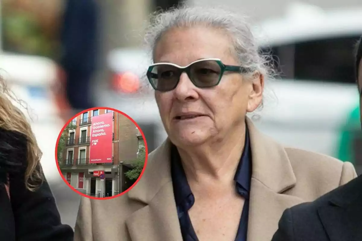 A person with sunglasses and gray hair walks down the street with a political sign in a box in the lower left corner.