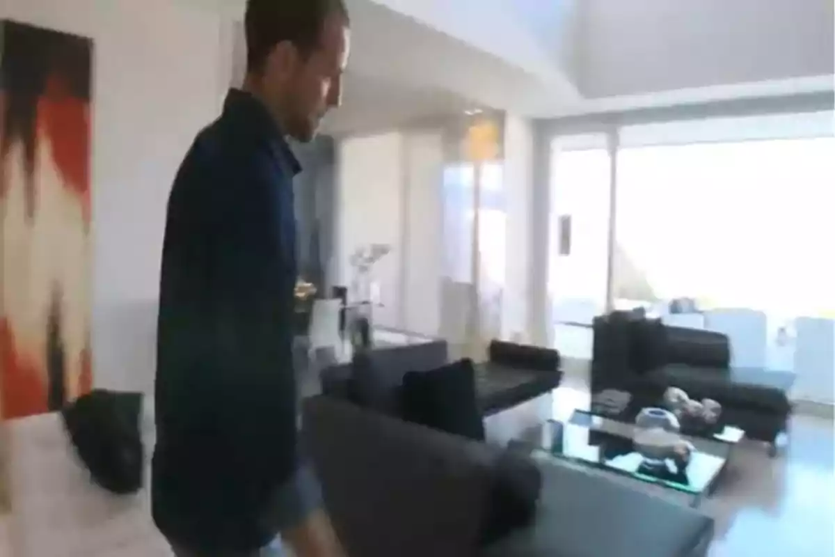 Gonzalo Miró camina por una sala de estar moderna con sofás oscuros y una gran ventana. Captura de 'Supercasas' Gonzalo Miró camina por una sala de estar moderna con sofás oscuros y una gran ventana. Captura de 'Supercasas'