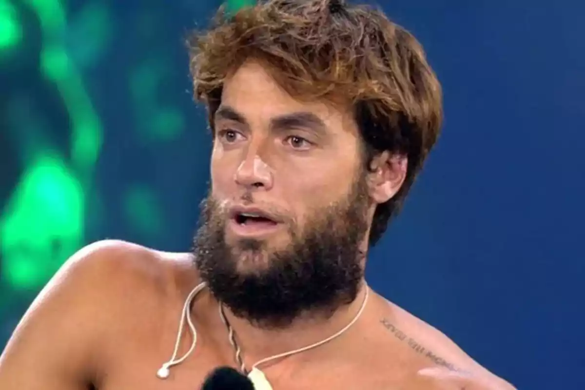 Montoya, sin camiseta, usando un collar y con un fondo azul y verde desenfocado. Captura de 'Supervivientes' Montoya, sin camiseta, usando un collar y con un fondo azul y verde desenfocado. Captura de 'Supervivientes'