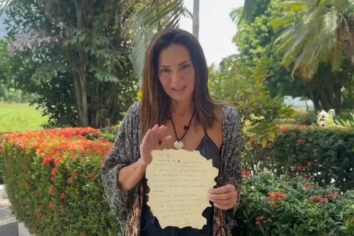 Olga Moreno sosteniendo una carta en un jardín con vegetación y flores. Captura de 'Supervivientes' el 7 de julio de 2024