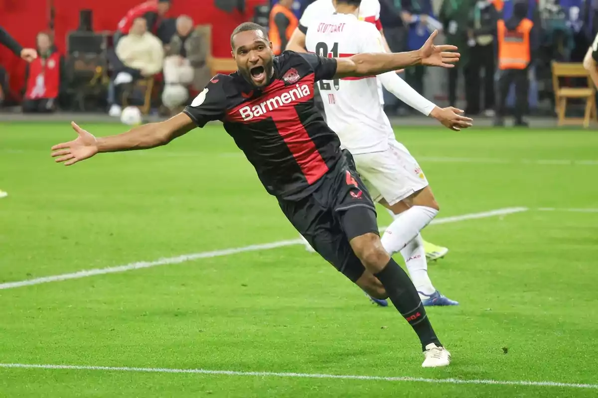 Jugador de fútbol celebrando un gol en el campo con los brazos extendidos y expresión de alegría.