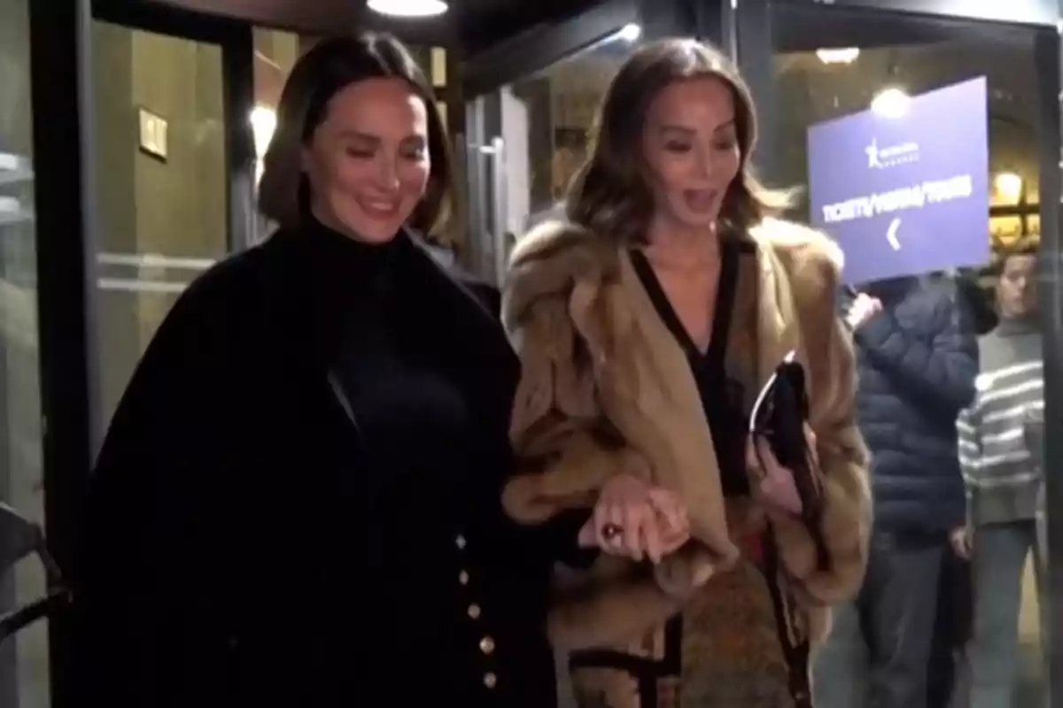 Tamara Falcó e Isabel Preysler sonrientes saliendo de un edificio, una de ellas lleva un abrigo de piel y la otra un abrigo oscuro. Tamara Falcó e Isabel Preysler sonrientes saliendo de un edificio, una de ellas lleva un abrigo de piel y la otra un abrigo oscuro.