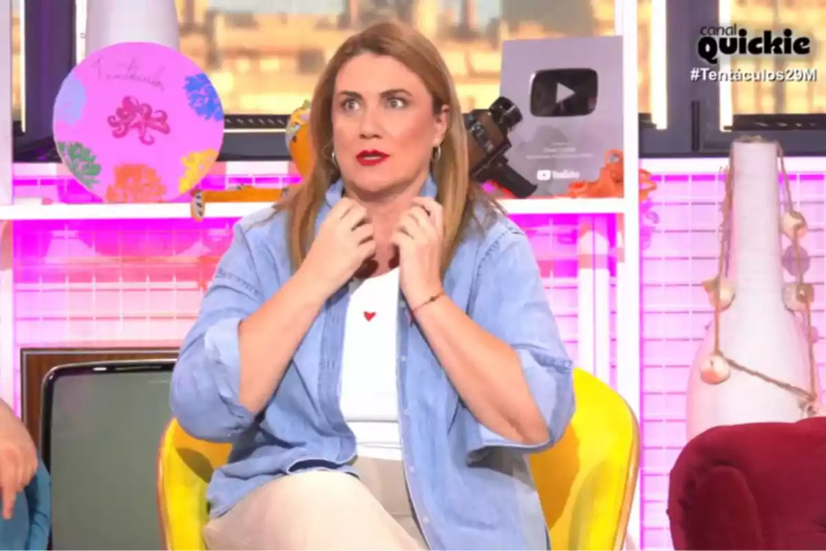 Carlota Corredera sentada en un sillón amarillo con expresión de sorpresa en un set colorido de programa de televisión. Captura de 'Tentáculos' Carlota Corredera sentada en un sillón amarillo con expresión de sorpresa en un set colorido de programa de televisión. Captura de 'Tentáculos'