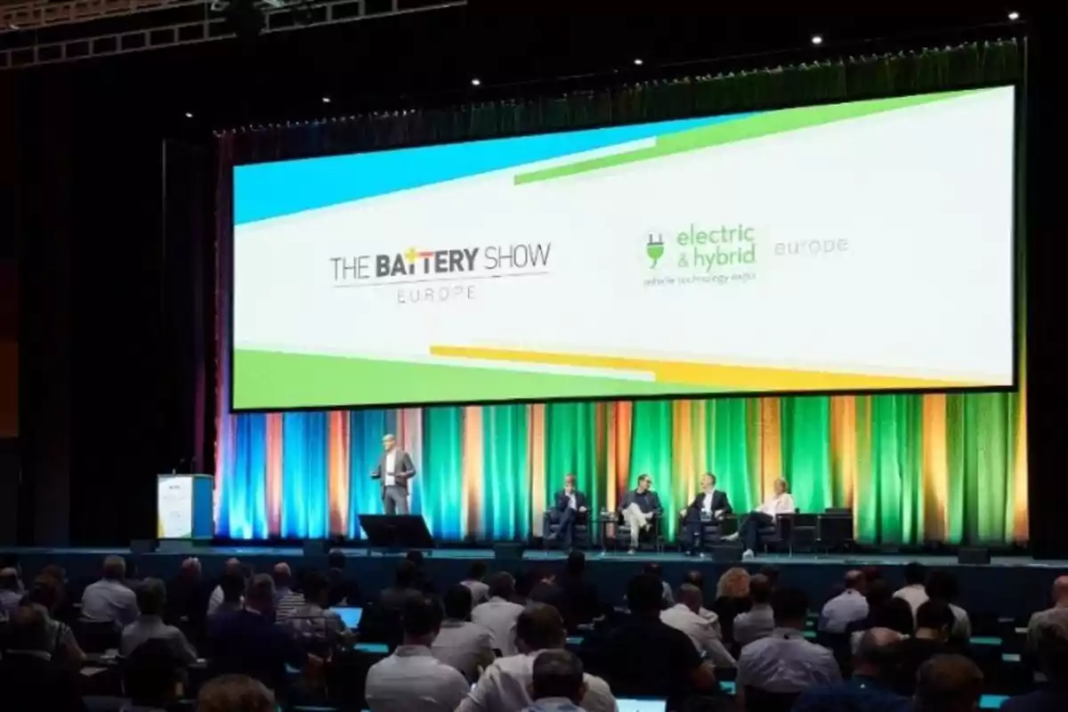 Una conferencia sobre tecnología de baterías y vehículos eléctricos en Europa, con un escenario iluminado y un público atento.