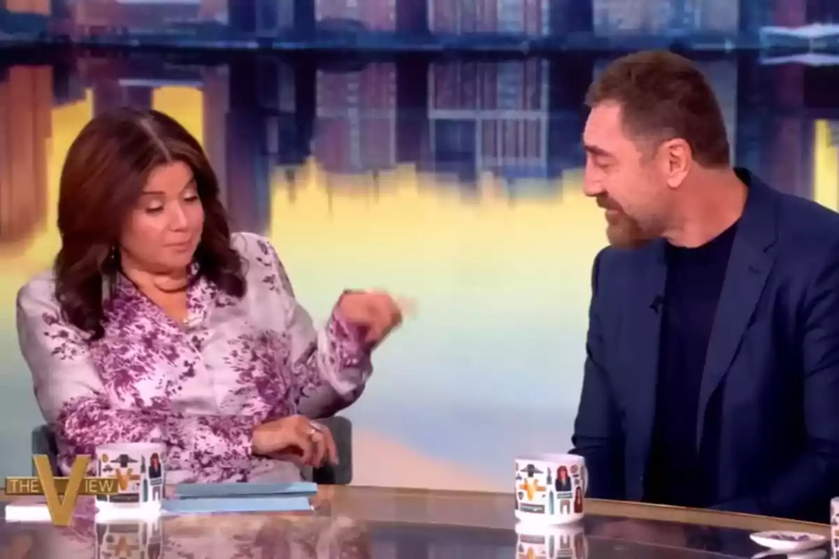 Javier Bardem y una presentadora conversan en un programa de televisión, sentadas en una mesa con tazas decoradas y un fondo de ciudad desenfocado. Captura de 'The View' Javier Bardem y una presentadora conversan en un programa de televisión, sentadas en una mesa con tazas decoradas y un fondo de ciudad desenfocado. Captura de 'The View'