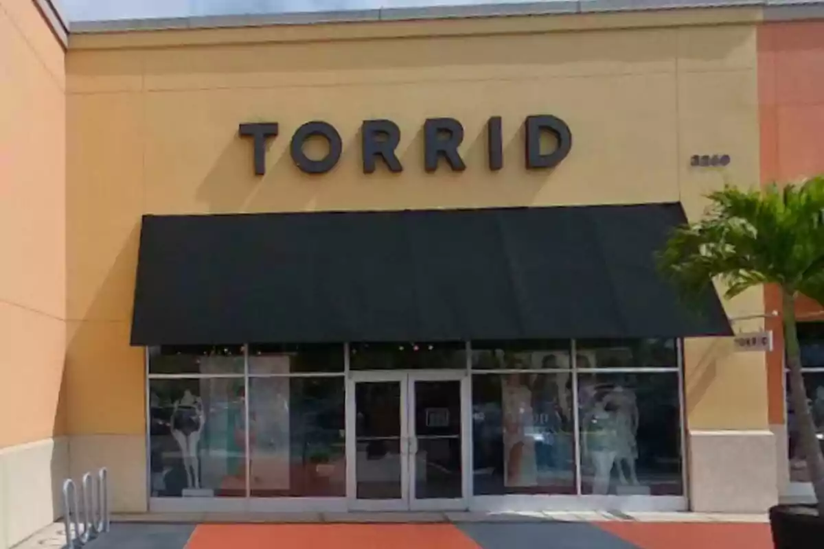 Storefront of a Torrid shop with a black awning and mannequins in the display window Storefront of a Torrid shop with a black awning and mannequins in the display window
