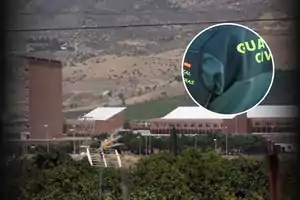 Edificio grande de ladrillo en un paisaje montañoso con un círculo que muestra un uniforme verde con texto en amarillo.