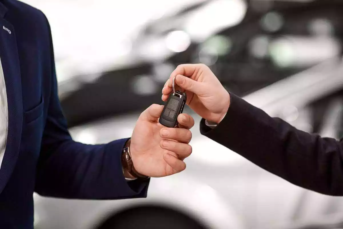 Primer plano de una persona que trabaja en un concesionario entregando las llaves del coche a un cliente