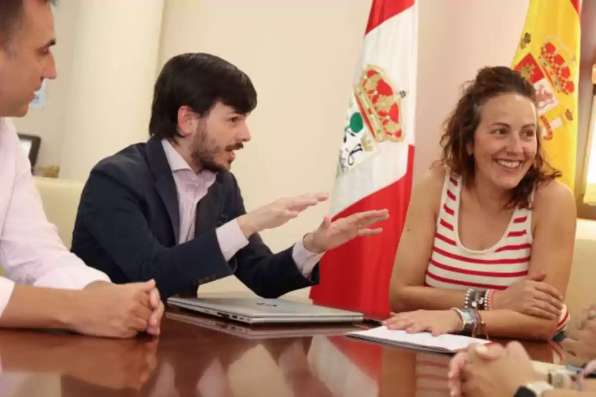 Personas conversando en una reunión con banderas de fondo.