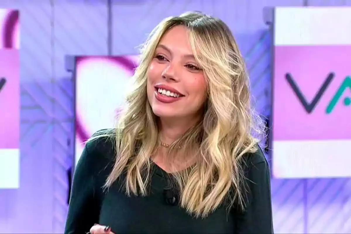 Alejandra Rubio with blonde hair smiles in a television studio with a colorful background. Capture from 'Vamos a ver'.