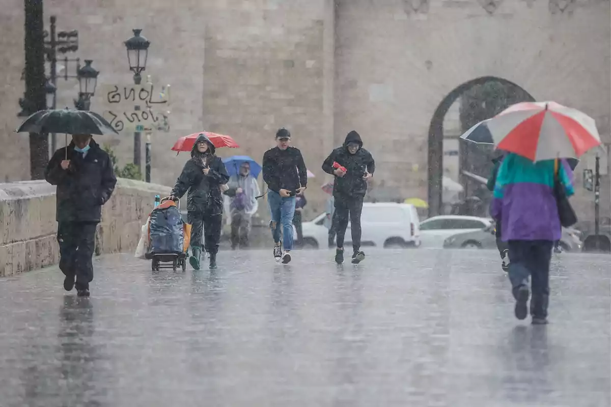 Personas caminando bajo la lluvia con paraguas en una calle urbana. Personas caminando bajo la lluvia con paraguas en una calle urbana.