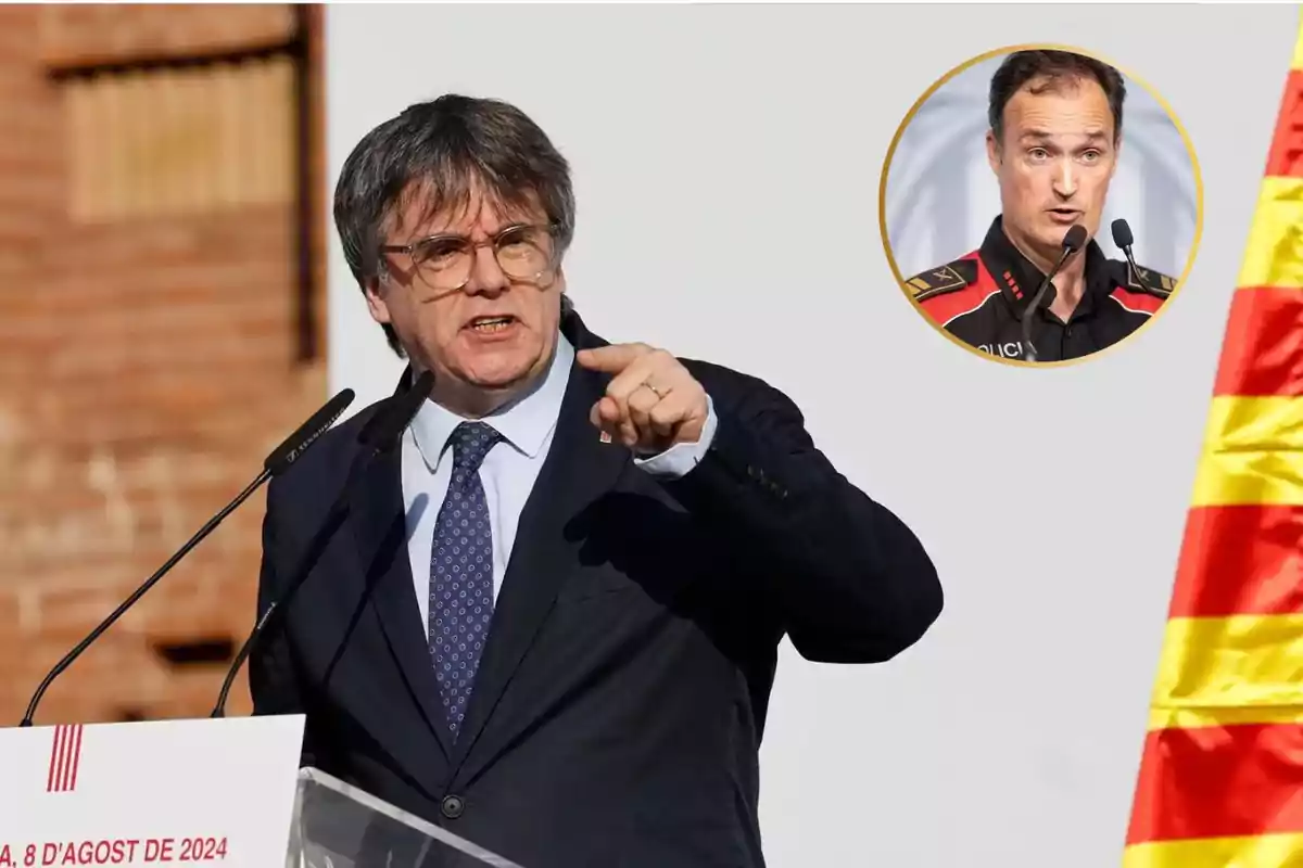 Un hombre de traje y corbata habla en un podio con un micrófono, señalando con el dedo, mientras una bandera catalana está a su derecha y un recuadro con la imagen de otro hombre con uniforme policial está en la esquina superior derecha.