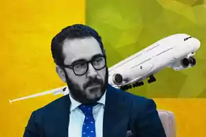 Un hombre con gafas y barba aparece en primer plano mientras un avión vuela en el fondo sobre un diseño geométrico amarillo y verde.