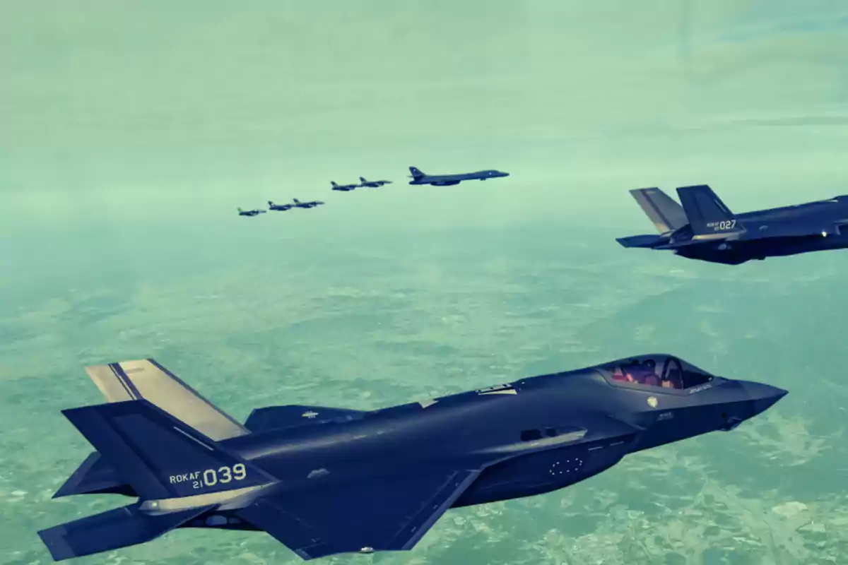 Varios aviones militares vuelan en formación sobre un paisaje visto desde el aire