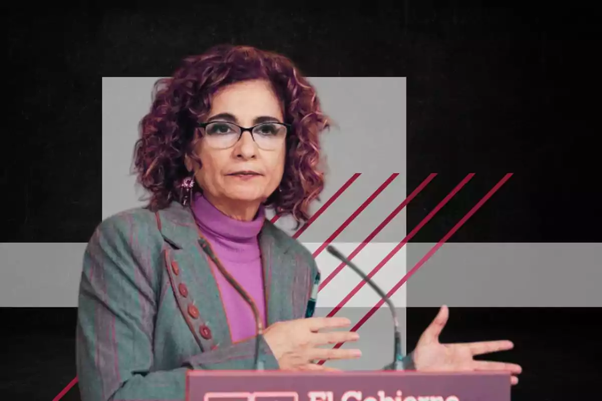 Una mujer con gafas y cabello rizado está hablando en un podio con un fondo geométrico.