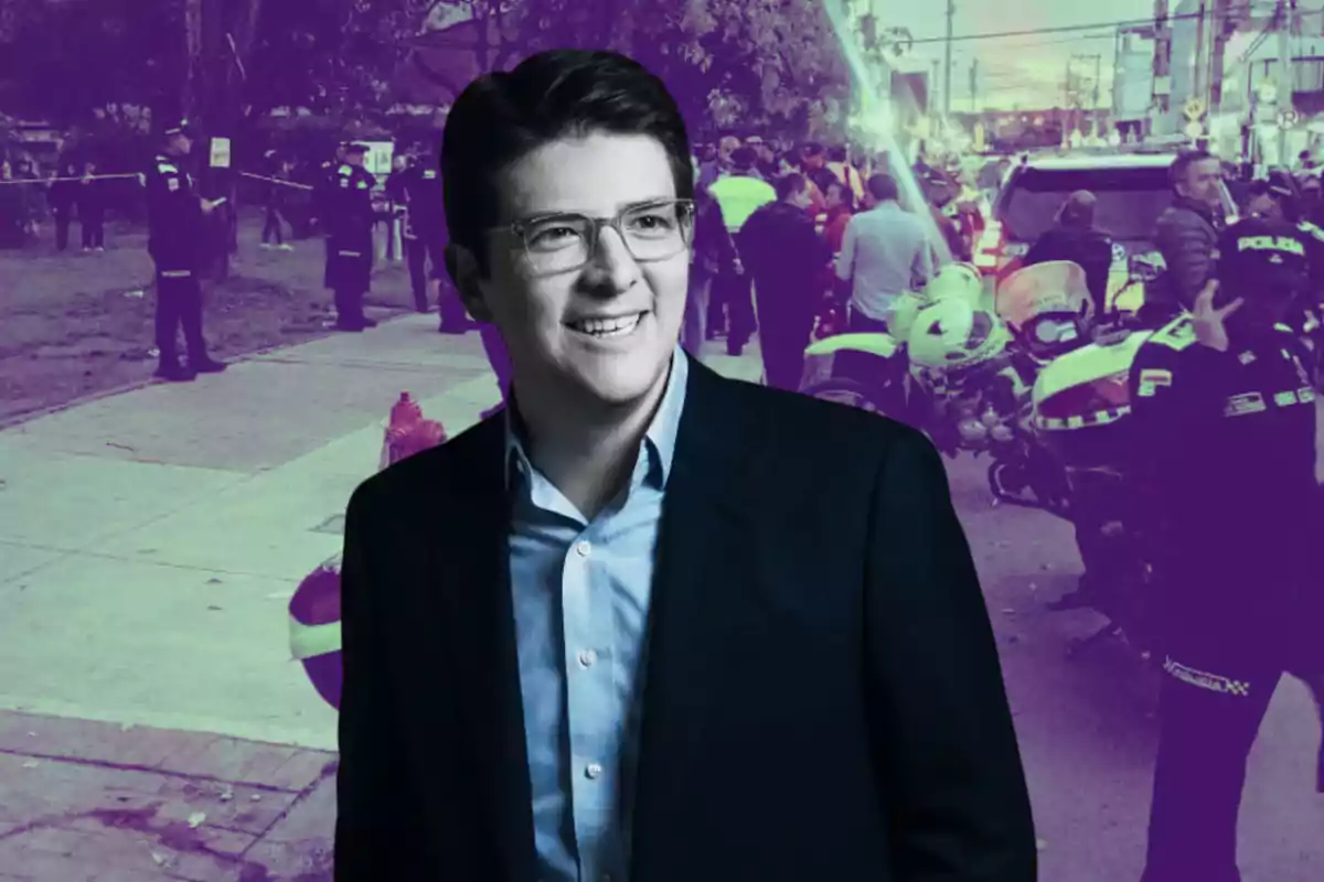 Un hombre joven con gafas y saco oscuro sonríe al frente de una escena urbana con presencia policial y patrullas al fondo, la imagen tiene un filtro en tonos morados.