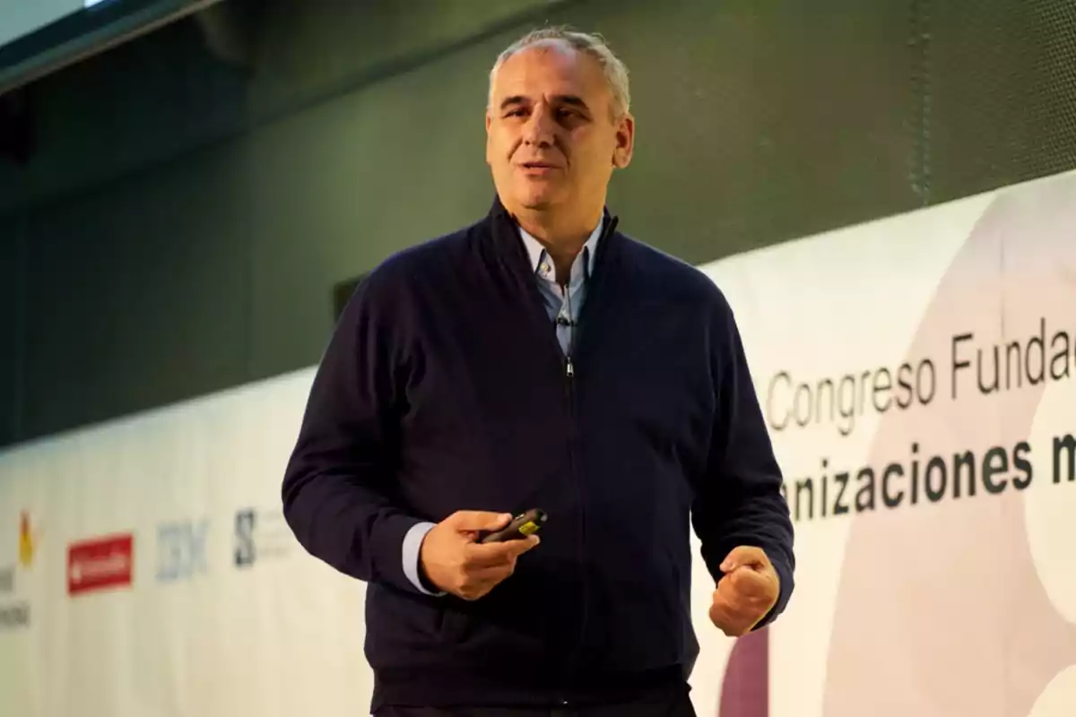 Hombre dando una conferencia en un congreso con fondo de pancarta.