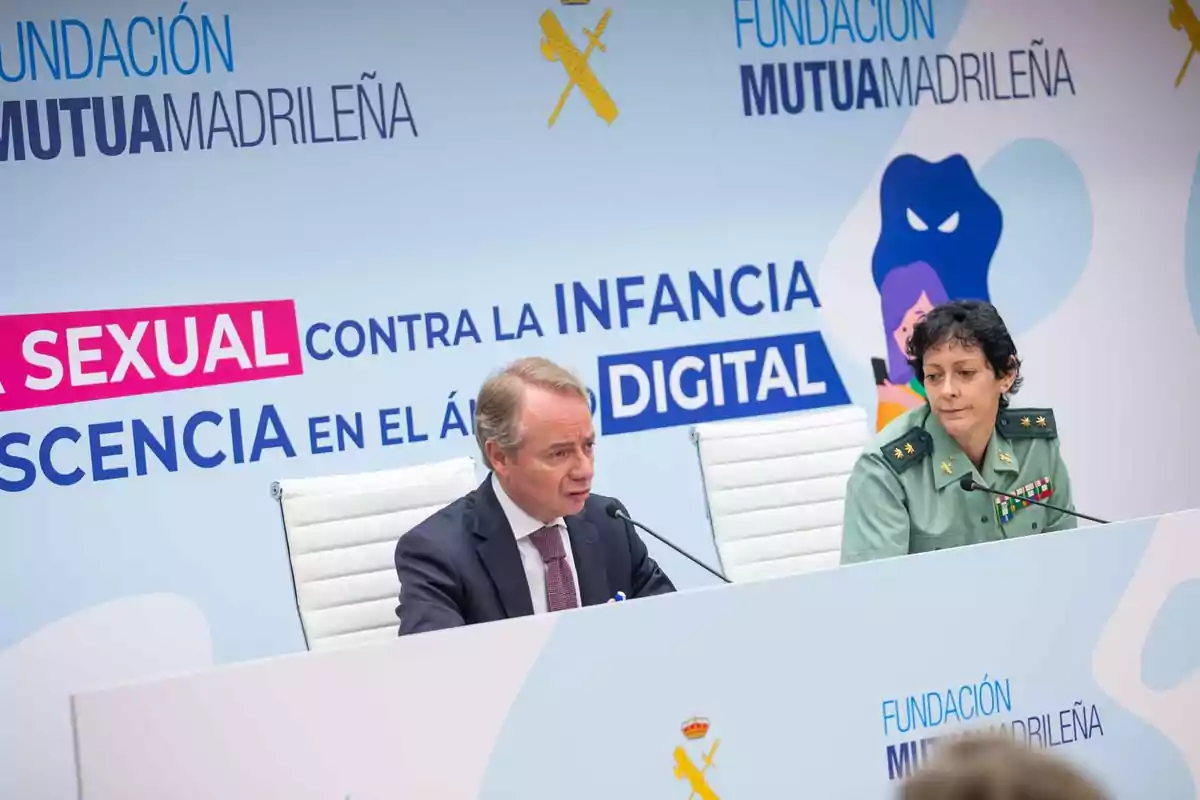 Dos personas están sentadas en una mesa durante un evento de la Fundación Mutua Madrileña, con un cartel que dice "Contra la violencia sexual en la infancia y adolescencia en el ámbito digital".