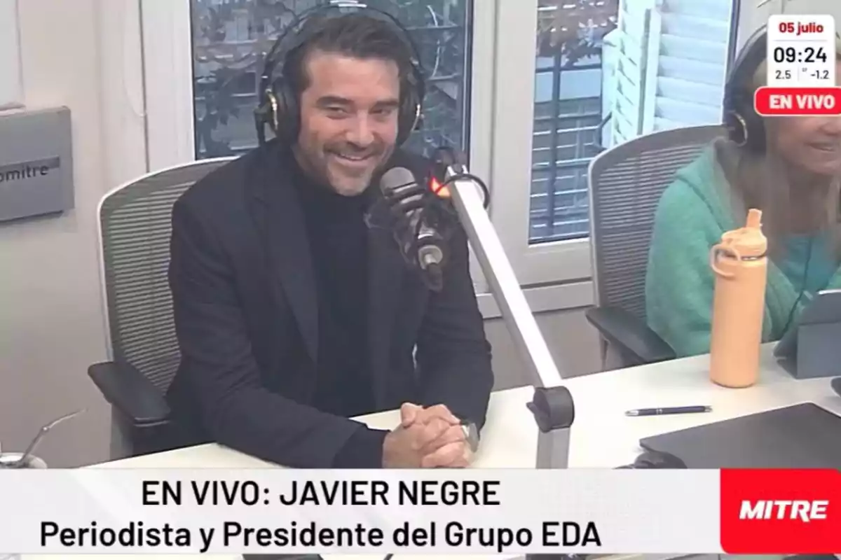 Un hombre con auriculares y micrófono en un estudio de radio, con un cartel que dice "EN VIVO: JAVIER NEGRE Periodista y Presidente del Grupo EDA" y el logo de MITRE.