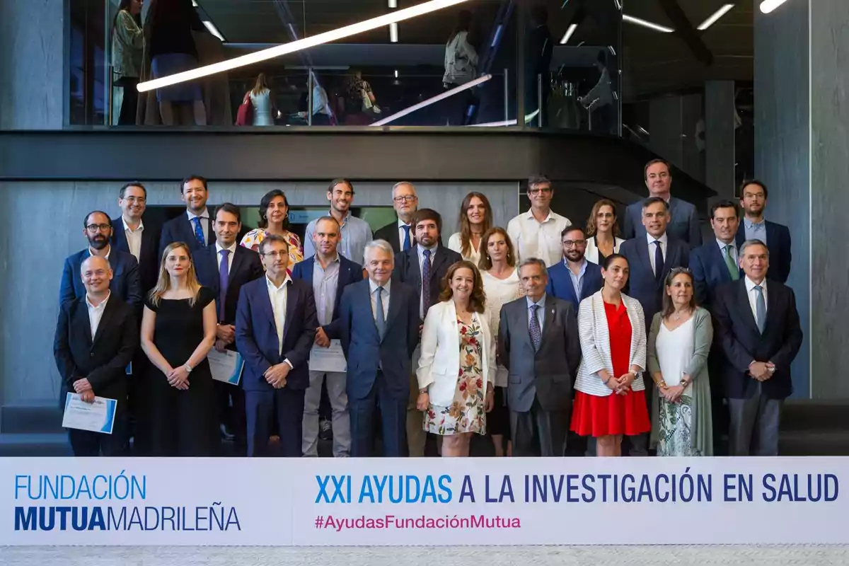 Grupo de personas posando en un evento de la Fundación Mutua Madrileña, con un cartel que dice "XXI Ayudas a la Investigación en Salud" y el hashtag #AyudasFundaciónMutua.