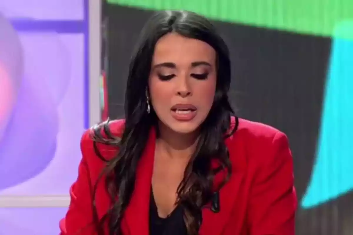 Una mujer con cabello oscuro y chaqueta roja está hablando en un entorno de estudio de televisión. Una mujer con cabello oscuro y chaqueta roja está hablando en un entorno de estudio de televisión.