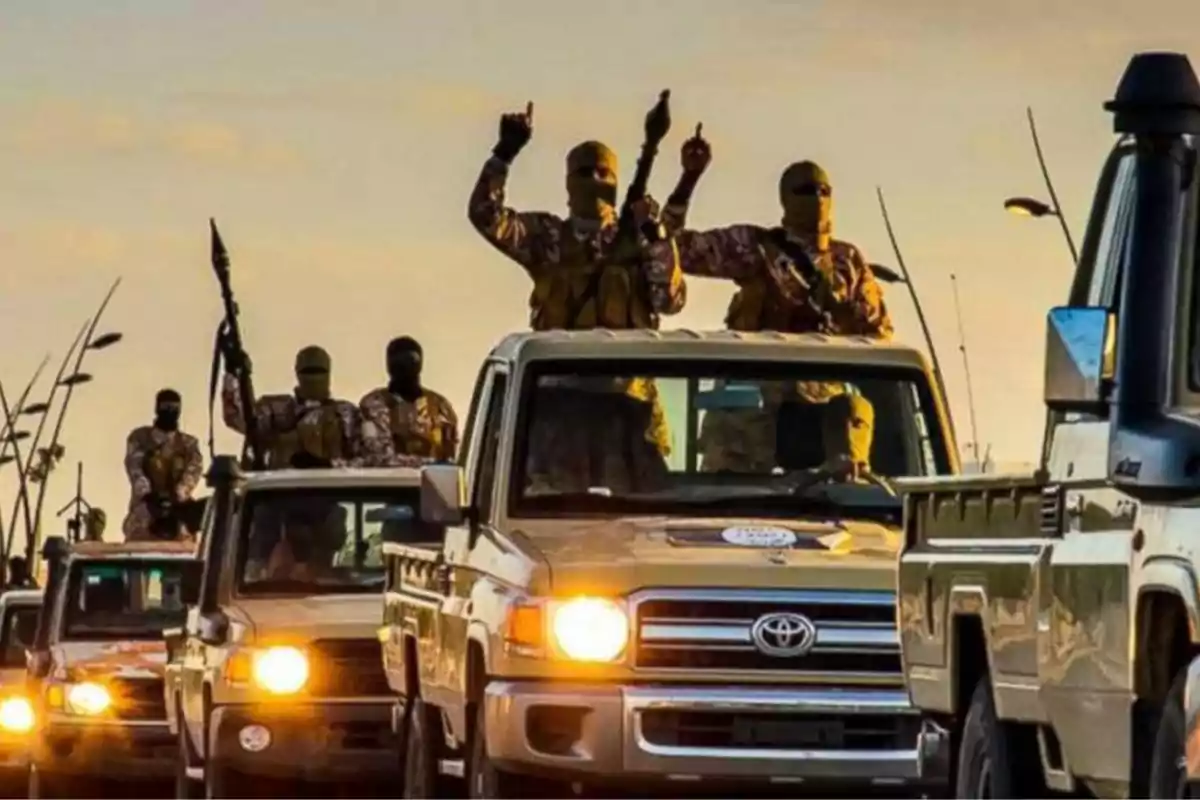Caravana de vehículos todoterreno con personas armadas y encapuchadas al atardecer Caravana de vehículos todoterreno con personas armadas y encapuchadas al atardecer